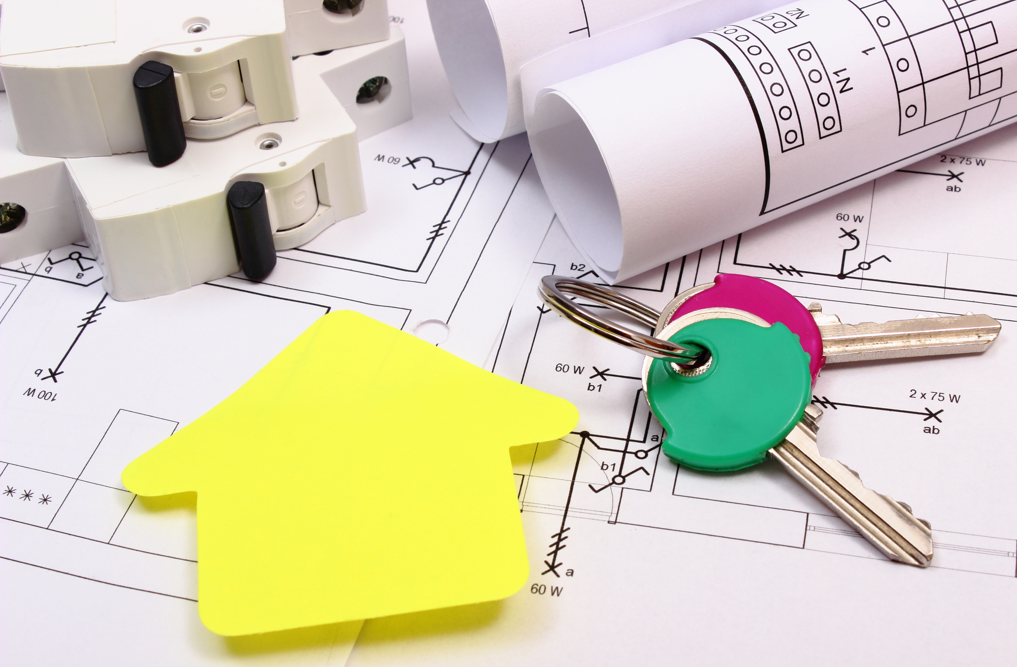 A yellow key and a house plan on top of a piece of paper.