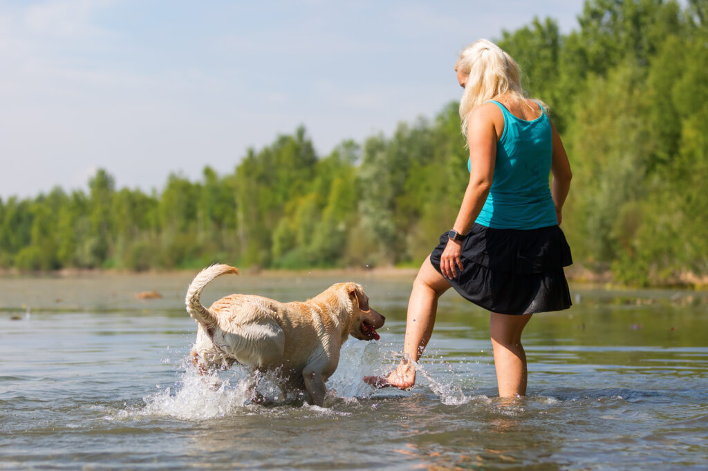 A woman is playing with her dog in the water.