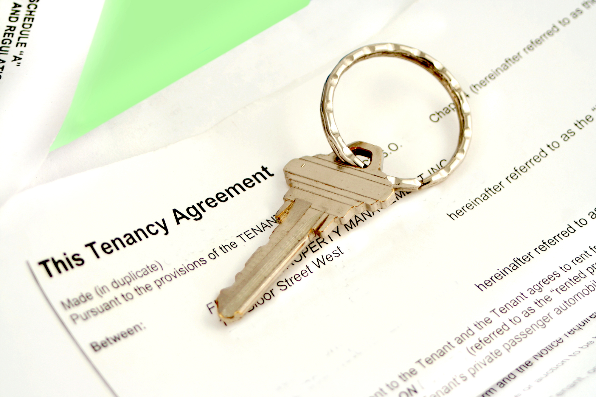 A key is sitting on top of a tenancy agreement.