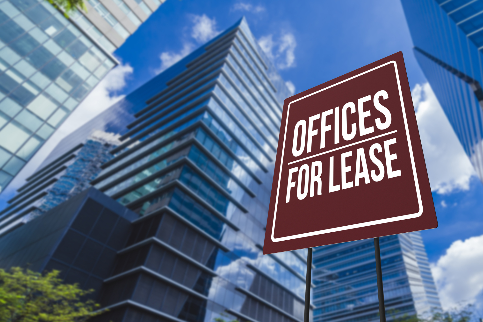 A sign that says offices for lease in front of tall buildings.
