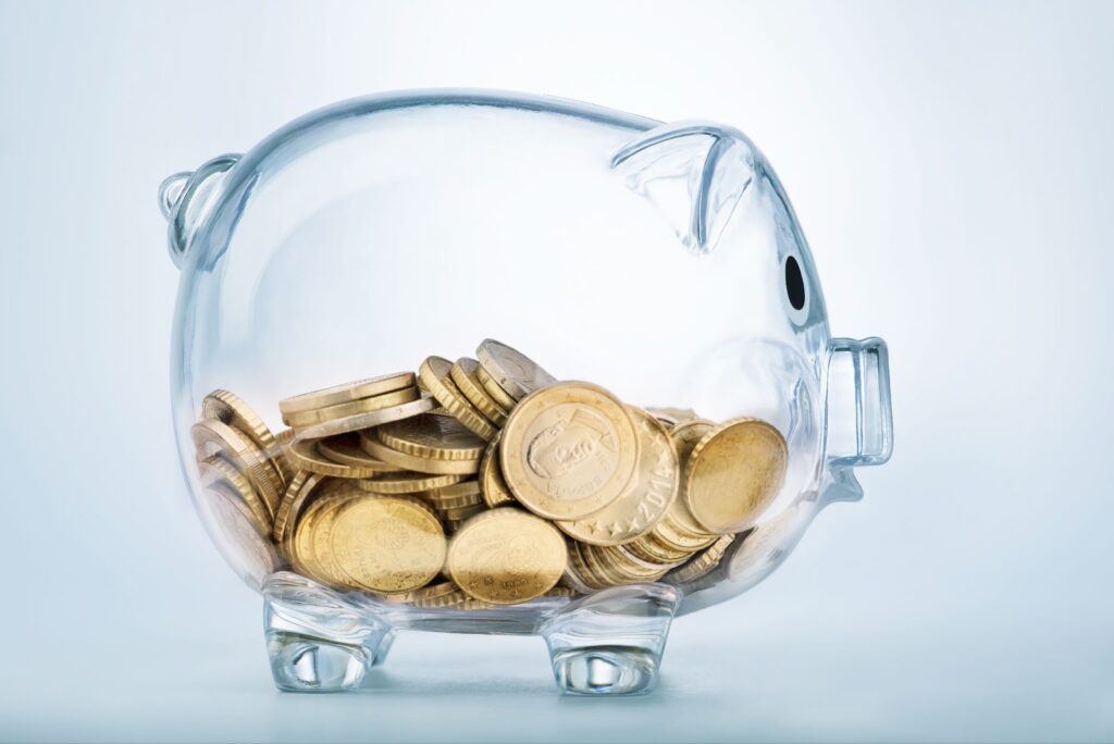 A glass piggy bank filled with gold coins.