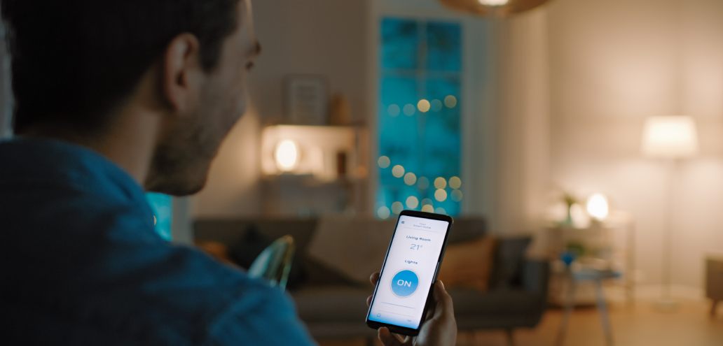A man using a smart phone in a smart home living room.