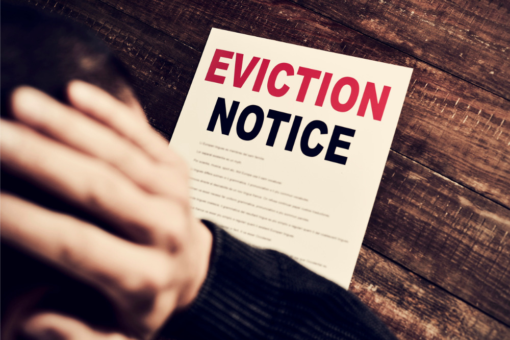 A person holding an eviction notice on a wooden table.