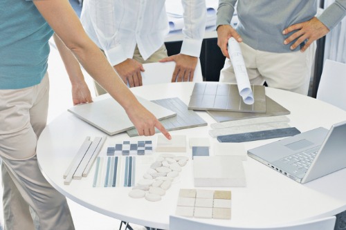 A group of people standing around a table with tile samples.