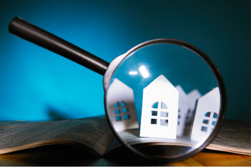 A magnifying glass with a house model on it.