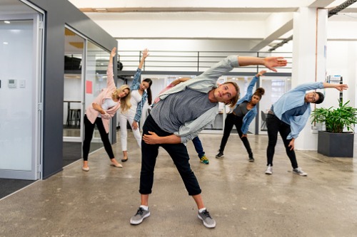 A group of people doing a dance routine in an office.