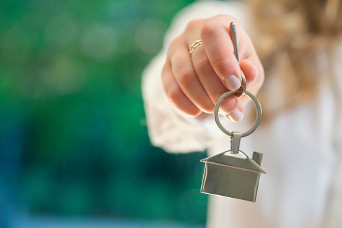 A woman holding a key to a house.