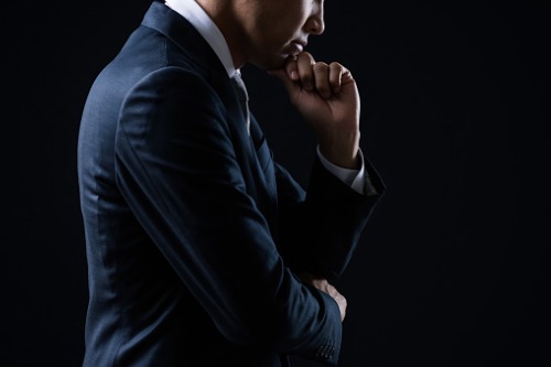 A businessman in a suit is looking at his hand.
