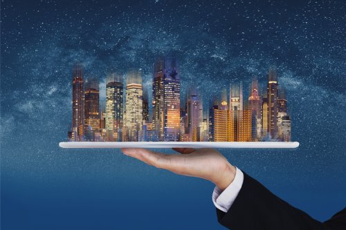 A businessman holding a tablet with a cityscape on it.