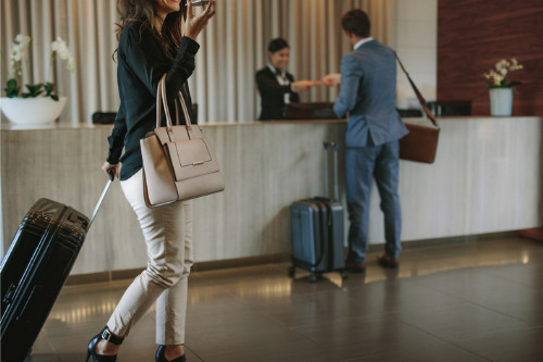 A woman in a business suit is standing in front of a hotel reception.