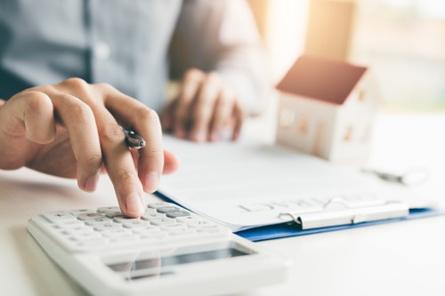 A man is using a calculator to calculate the cost of buying a house.