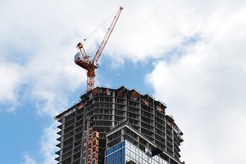 A construction crane is on top of a tall building.