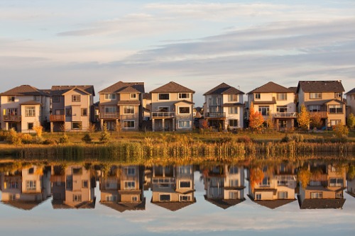 A row of houses reflected in a lake.