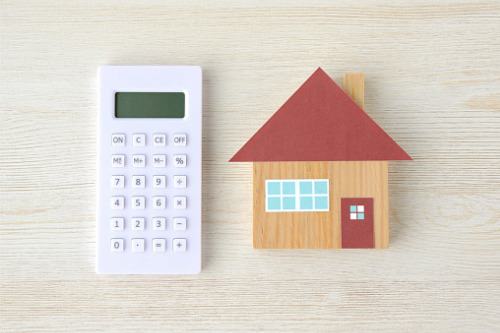 A house model and calculator on a wooden table.