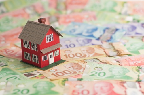 A red house on top of a pile of canadian money.