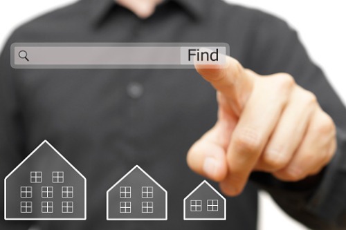 A man is pointing at a search button with a house on it.
