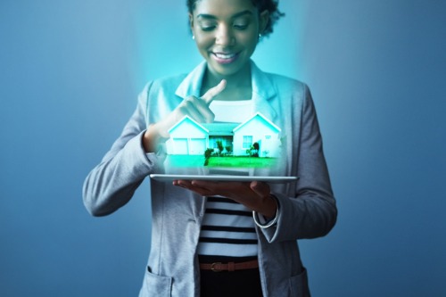 A woman holding a tablet with a house on it.