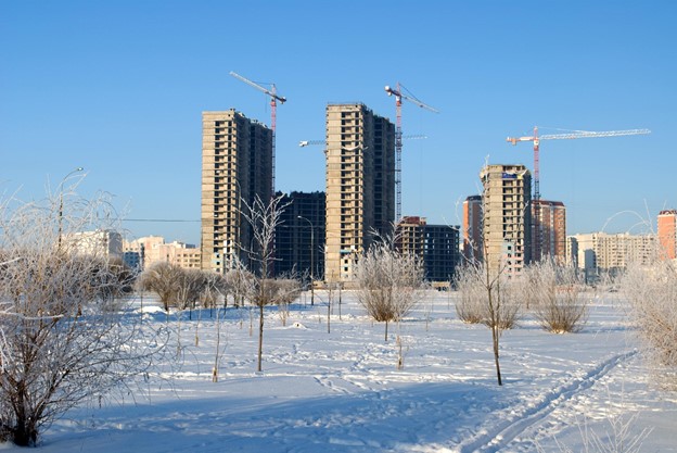 A winter scene with tall buildings and trees in the background.