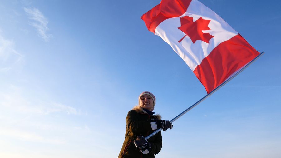 A woman holding a canadian flag in the sky.