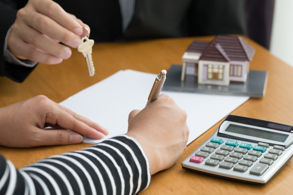 A woman holding a key to a house and a calculator.