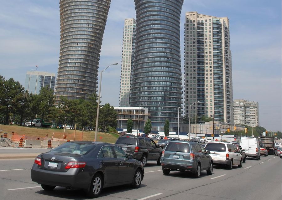 Cars are driving down a street with tall buildings in the background.