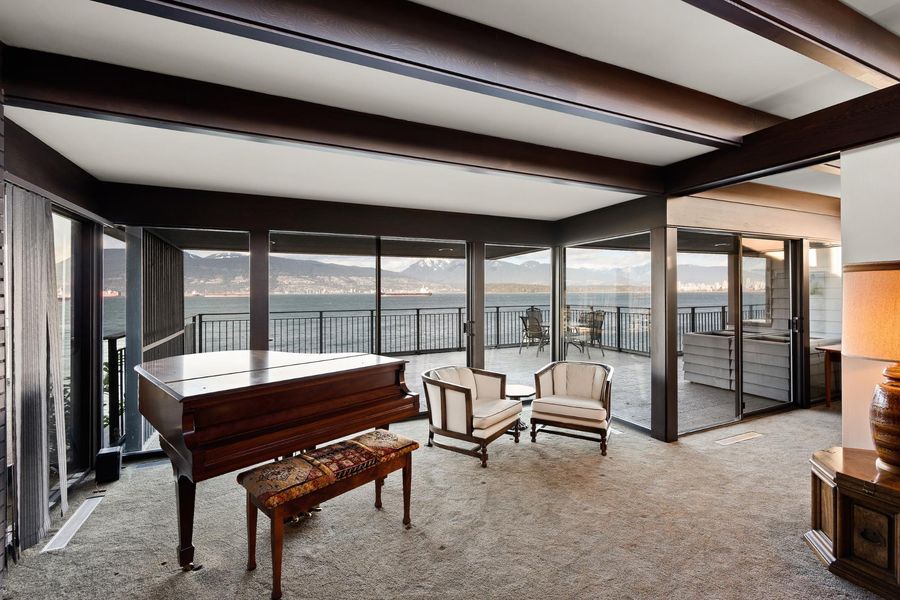 A living room with a piano and a view of the water.