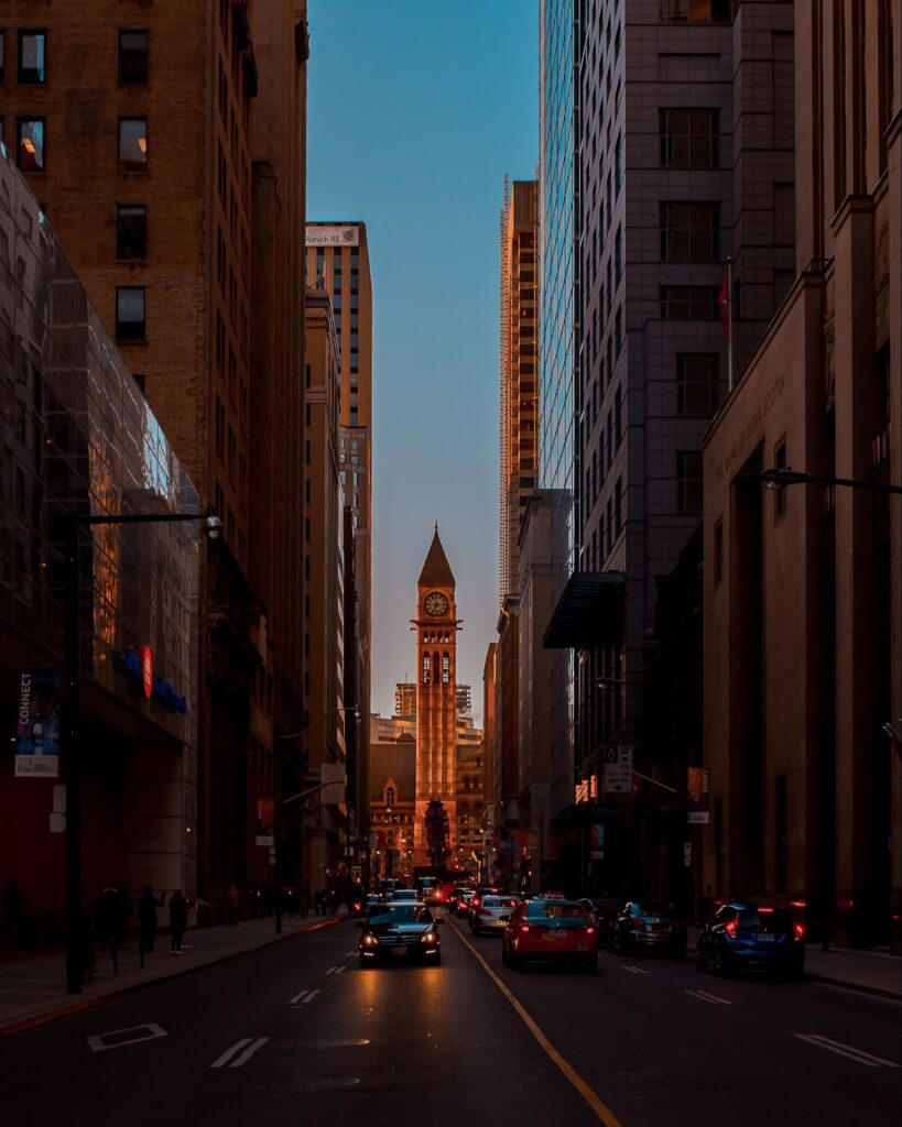 A city street with tall buildings and a clock tower.