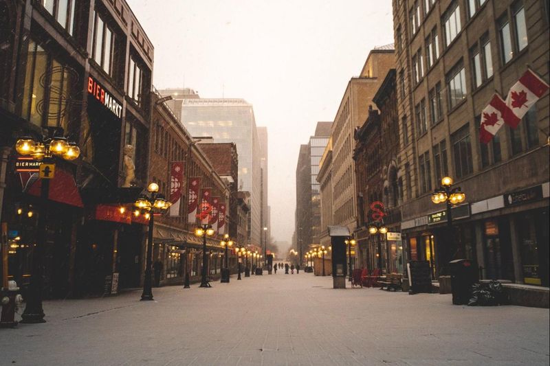 A snowy street with buildings and a canadian flag.