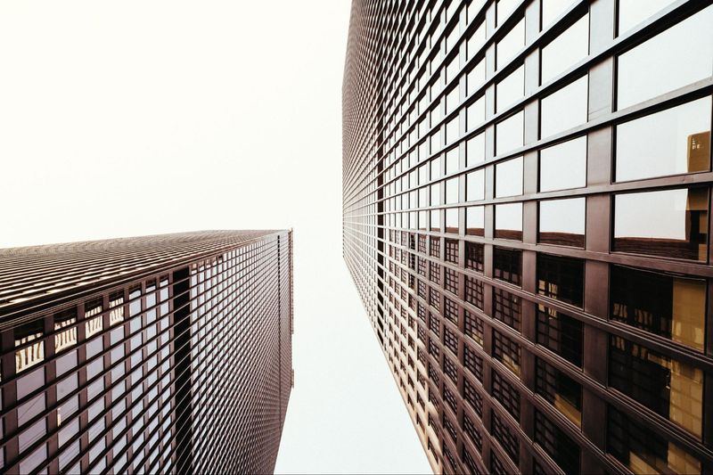 A view of two tall buildings looking up at each other.