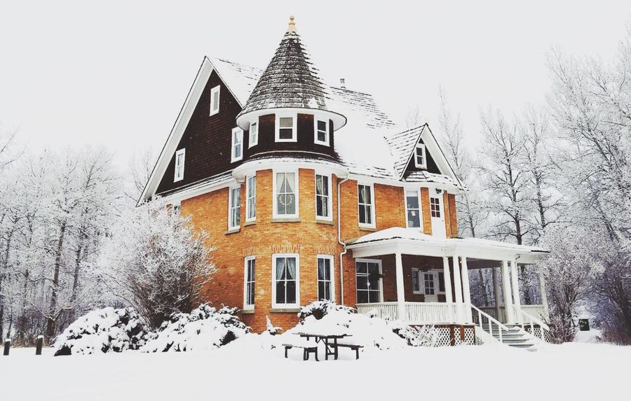 An old victorian house covered in snow.