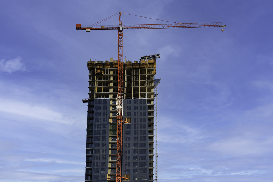 A tall building under construction with a crane in the background.