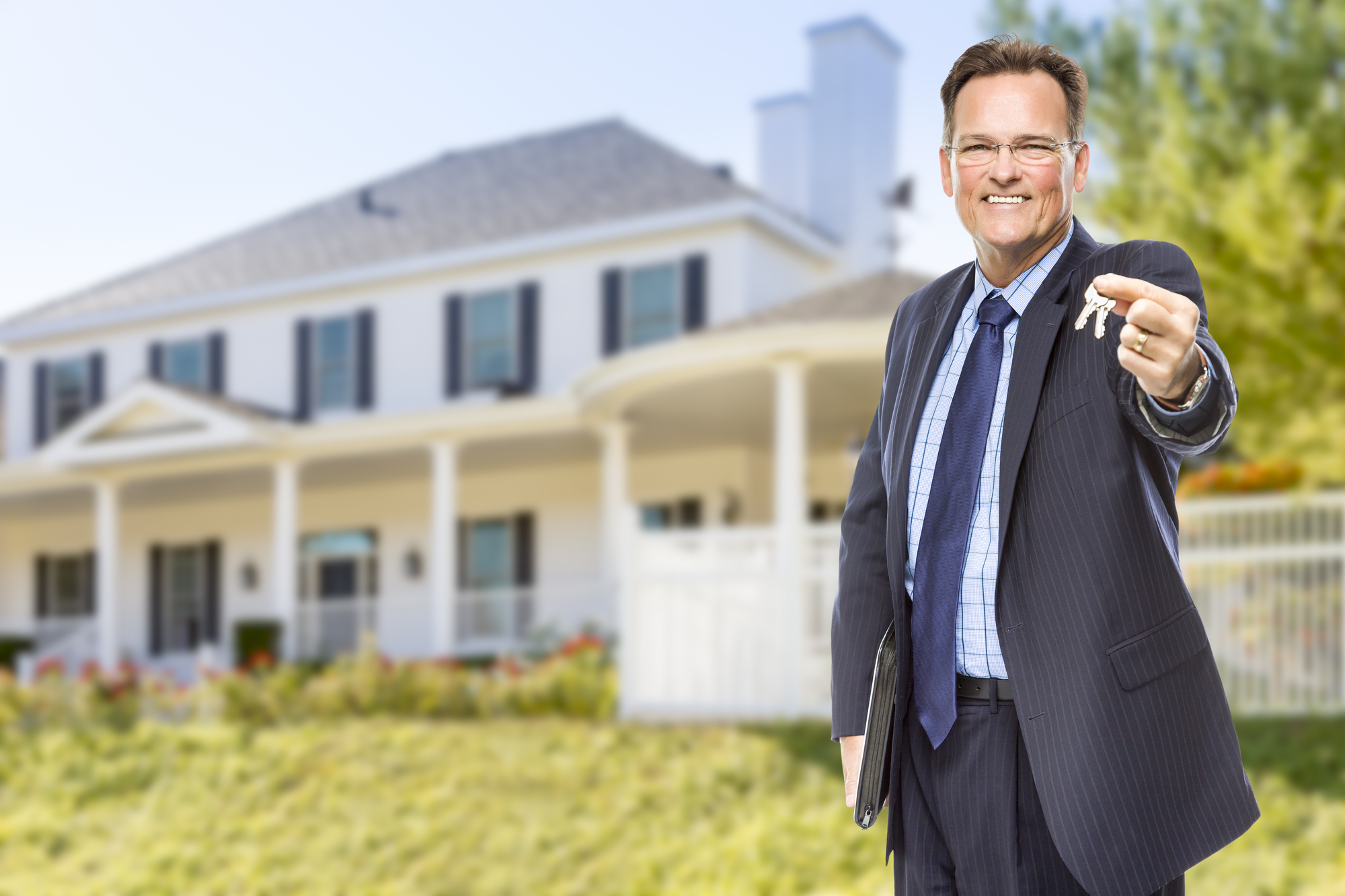 Real Estate Agent with House Keys in Front of Beautiful Home.