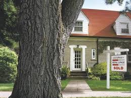 A house with a sold sign in front of a tree.