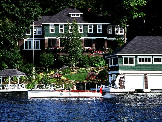 A house on a lake with a boat in front of it.