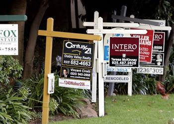 A row of real estate signs in front of a house.