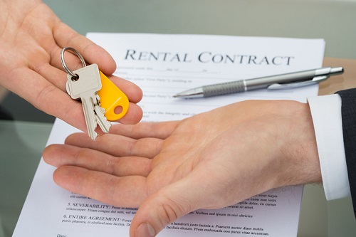 A person handing over a rental contract to another person.