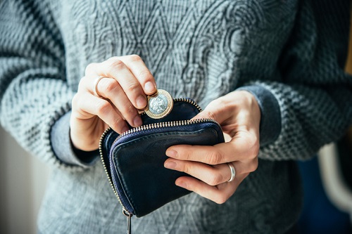 A woman is holding a coin in her purse.