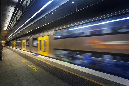 A train is moving at a station with a blurred background.