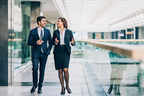 Two business people walking in an office building.