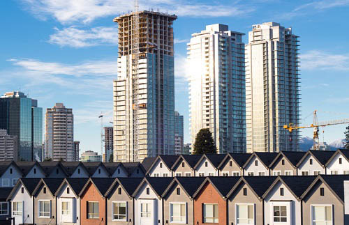 A row of houses with tall buildings in the background.