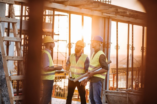 Three construction workers standing at a construction site.