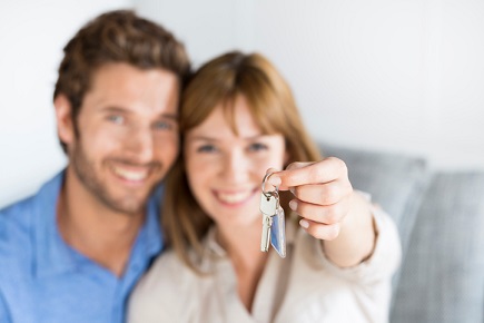 A couple holding up a key to their new home.