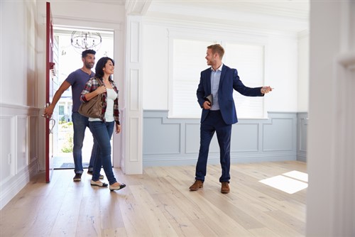 A group of people standing in a hallway in a new home.