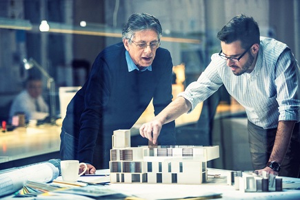 Two architects looking at a model of a building.
