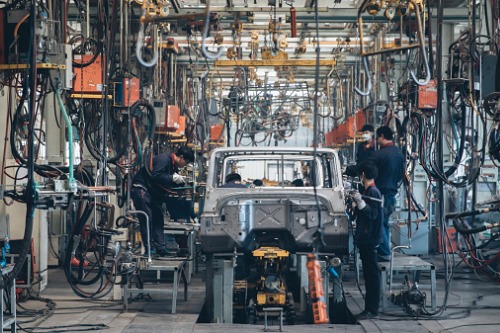 Workers working on a vehicle in a factory.