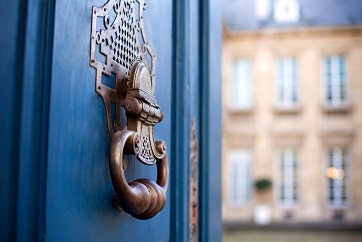A blue door with an ornate door handle.