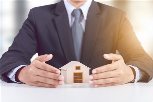Businessman holding a house model in his hands.