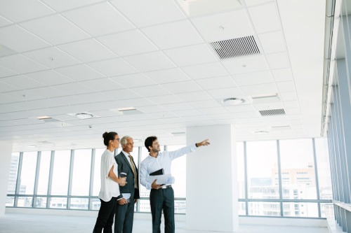 Three business people pointing at a window in an office.