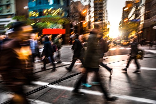 A blurry image of people crossing a street in a city.