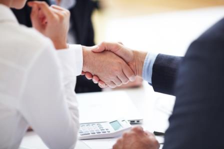 Two business people shaking hands at a meeting.